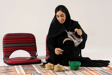 امرأة سعودية تصب القهوة العربية بالدلة والزي التقليدي