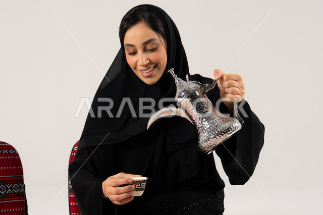 امرأة سعودية تصب القهوة العربية من دلة فضية