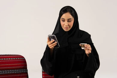 امرأة سعودية تستخدم الجوال مع فنجان قهوة عربية