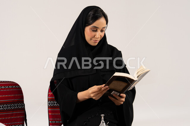 امرأة سعودية بالعباءة السوداء تقرأ كتاباً