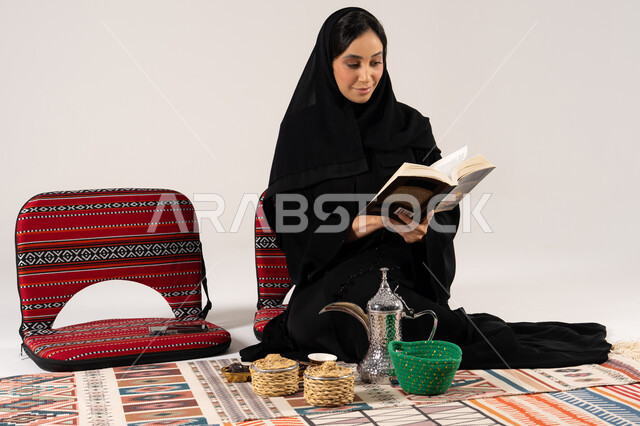 Saudi Woman in Abaya Reading Near Coffee Dallah