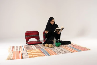 امرأة سعودية تقرأ كتاباً في جلسة عربية تراثية