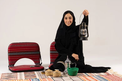امرأة سعودية تحمل فانوساً مع ديكور تراثي تقليدي