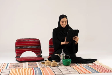 امرأة سعودية تستخدم جهاز لوحي في جلسة شعبية