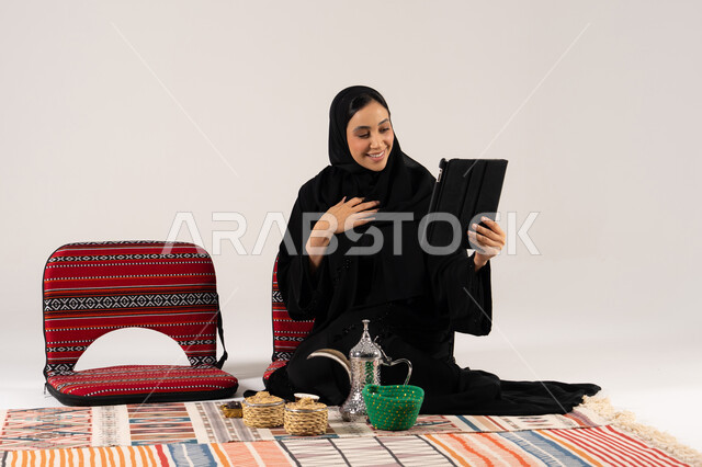 امرأة سعودية تستخدم جهازاً لوحياً في جلسة شعبية