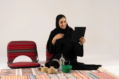 امرأة سعودية تستخدم جهازاً لوحياً في جلسة شعبية