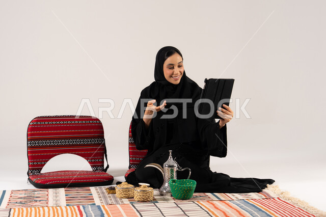 امرأة سعودية تستخدم الجهاز اللوحي في جلسة شعبية