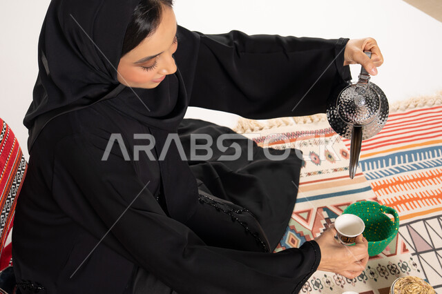 امرأة سعودية تصب القهوة العربية بالعباءة التقليدية