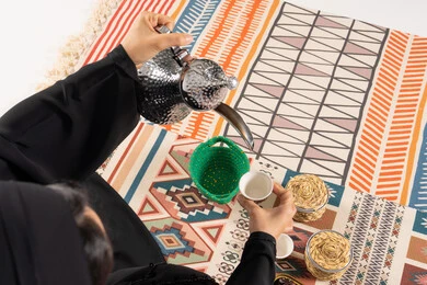 امرأة تصب القهوة العربية من دلة فضية