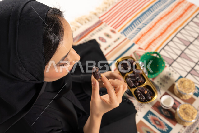امرأة عربية تأكل التمر على سجادة تقليدية