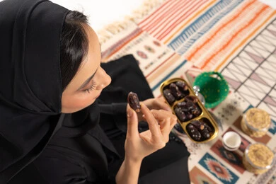 Arab Woman Eating Dates on Traditional Rug