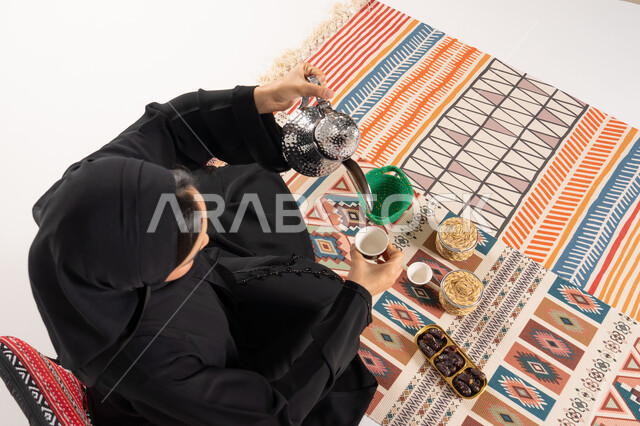 امرأة إماراتية تسكب القهوة العربية على سجادة تقليدية