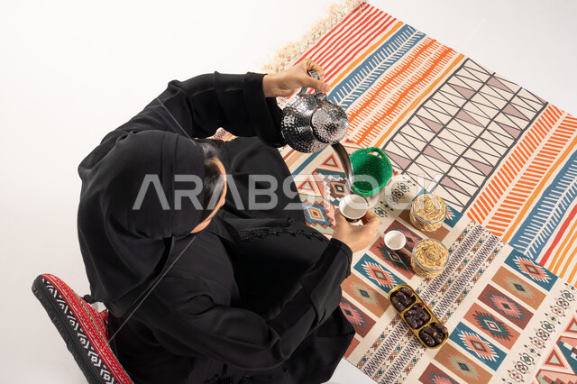 امرأة إماراتية تسكب القهوة العربية على سجادة تقليدية