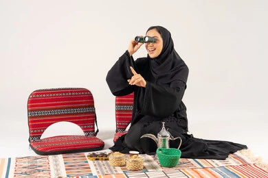 امرأة سعودية بالعباءة تنظر بالمنظار في الاستوديو