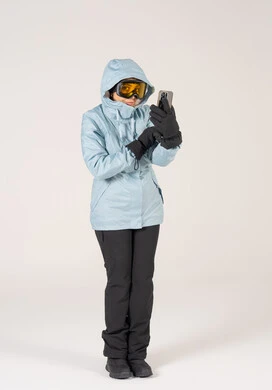 امرأة بملابس التزلج الشتوية تستخدم الهاتف الذكي