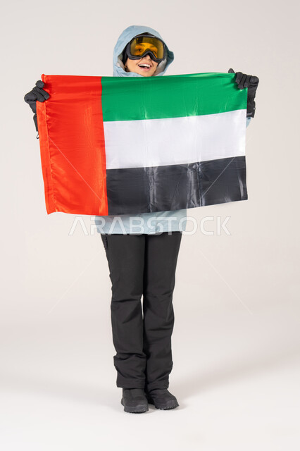 امرأة إماراتية بملابس التزلج تحمل علم الإمارات في الاستوديو