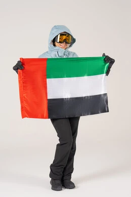 امرأة بملابس رياضية شتوية تحمل علم الإمارات