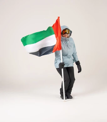امرأة إماراتية بملابس التزلج تحمل علم الإمارات