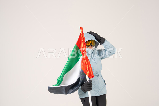 شخص يحمل علم الإمارات بملابس التزلج الشتوية
