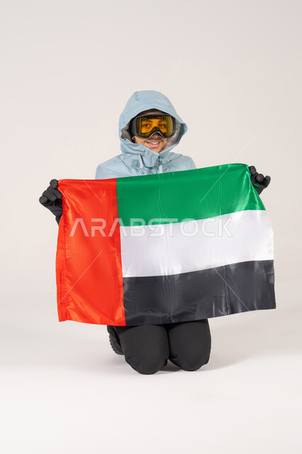 رجل بملابس التزلج يحمل علم الإمارات على خلفية بيضاء