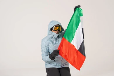 امرأة إماراتية بملابس الشتاء تمسك علم الإمارات