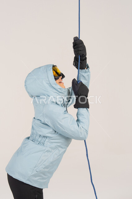 Woman in Winter Gear Pulling Climbing Rope
