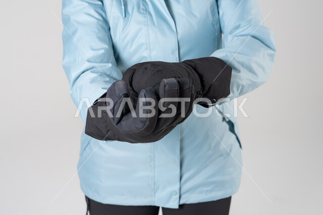 Person Adjusting Black Winter Gloves in Blue Jacket