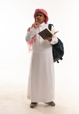 طالب سعودي بالثوب التقليدي يحمل كتاباً