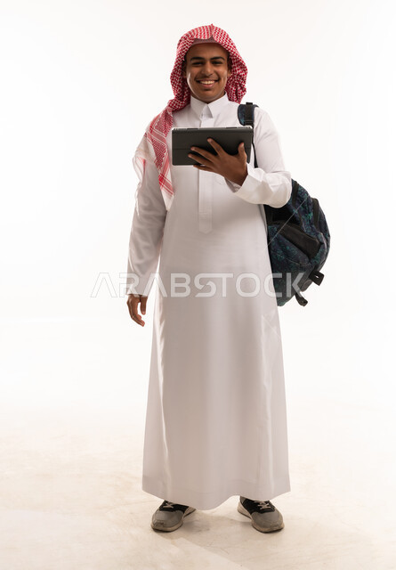 شاب سعودي يحمل جهاز لوحي وحقيبة ظهر