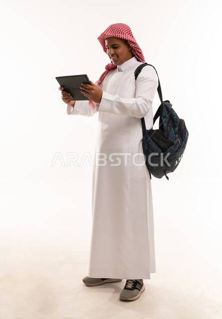 طالب سعودي بالزي التقليدي يستخدم جهاز لوحي