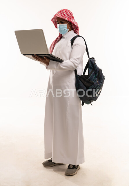 طالب سعودي يحمل لابتوب مع كمامة خلفية بيضاء