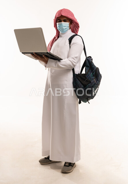 رجل سعودي بجهاز كمبيوتر محمول وكمامة في الاستوديو