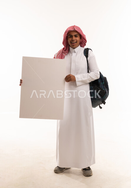 طالب سعودي يحمل لوحة فارغة على خلفية بيضاء
