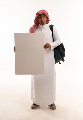 طالب سعودي يحمل لوحة بيضاء فارغة بتعبير مندهش