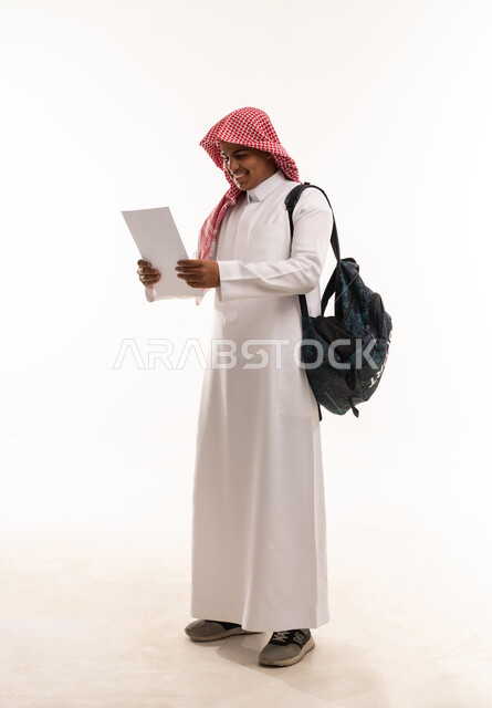 طالب سعودي بالزي التقليدي يحمل ورقة دراسية