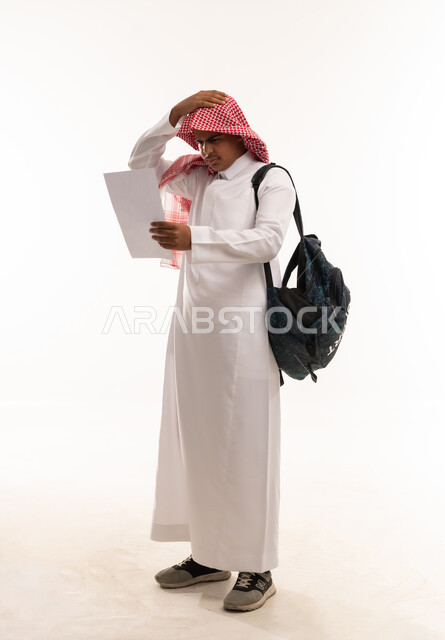 طالب سعودي يشعر بالتوتر ينظر إلى ورقة بخلفية بيضاء