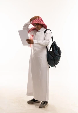 طالب سعودي يشعر بالتوتر ينظر إلى ورقة بخلفية بيضاء طالب سعودي يشعر بالتوتر ينظر إلى ورقة بخلفية بيضاء
