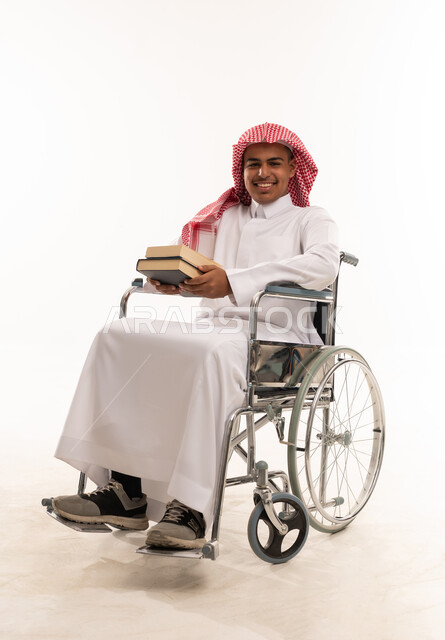 رجل سعودي على كرسي متحرك يمسك كتبا في استوديو
