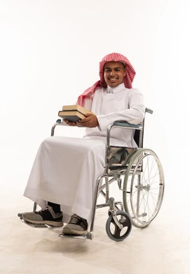 رجل سعودي على كرسي متحرك يمسك كتبا في استوديو