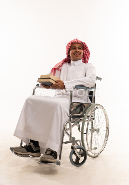رجل سعودي على كرسي متحرك يحمل كتباً بخلفية بيضاء