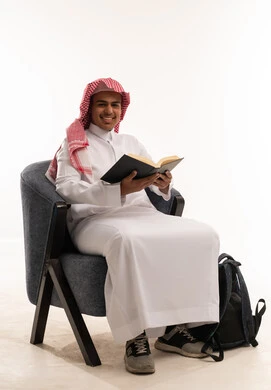 رجل سعودي بالزي التقليدي يقرأ كتاباً في الاستوديو