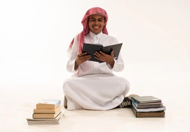 شاب سعودي بالزي التقليدي يقرأ كتاباً في الاستوديو