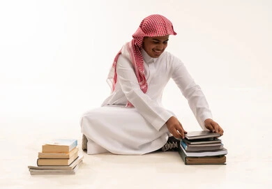 طالب سعودي مع كتب على خلفية بيضاء