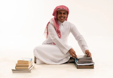 طالب سعودي بالزي التقليدي مع كتب دراسية