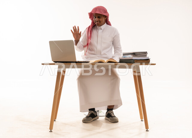 رجل سعودي يستخدم اللابتوب على خلفية بيضاء
