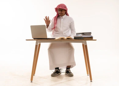 رجل سعودي يستخدم اللابتوب على خلفية بيضاء