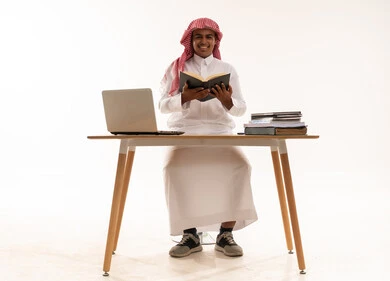 رجل سعودي يقرأ على مكتب مع كمبيوتر محمول