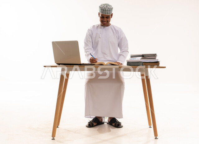 Omani Man Working at Desk with Laptop and Books