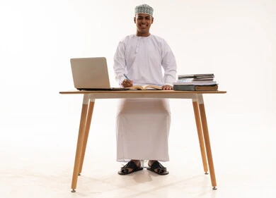 Omani Man at Desk with Laptop and Books