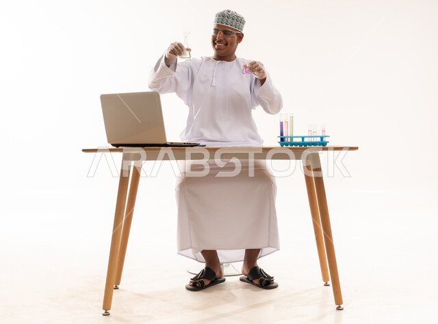عالم عماني يعمل على أبحاث كيميائية مع لابتوب
